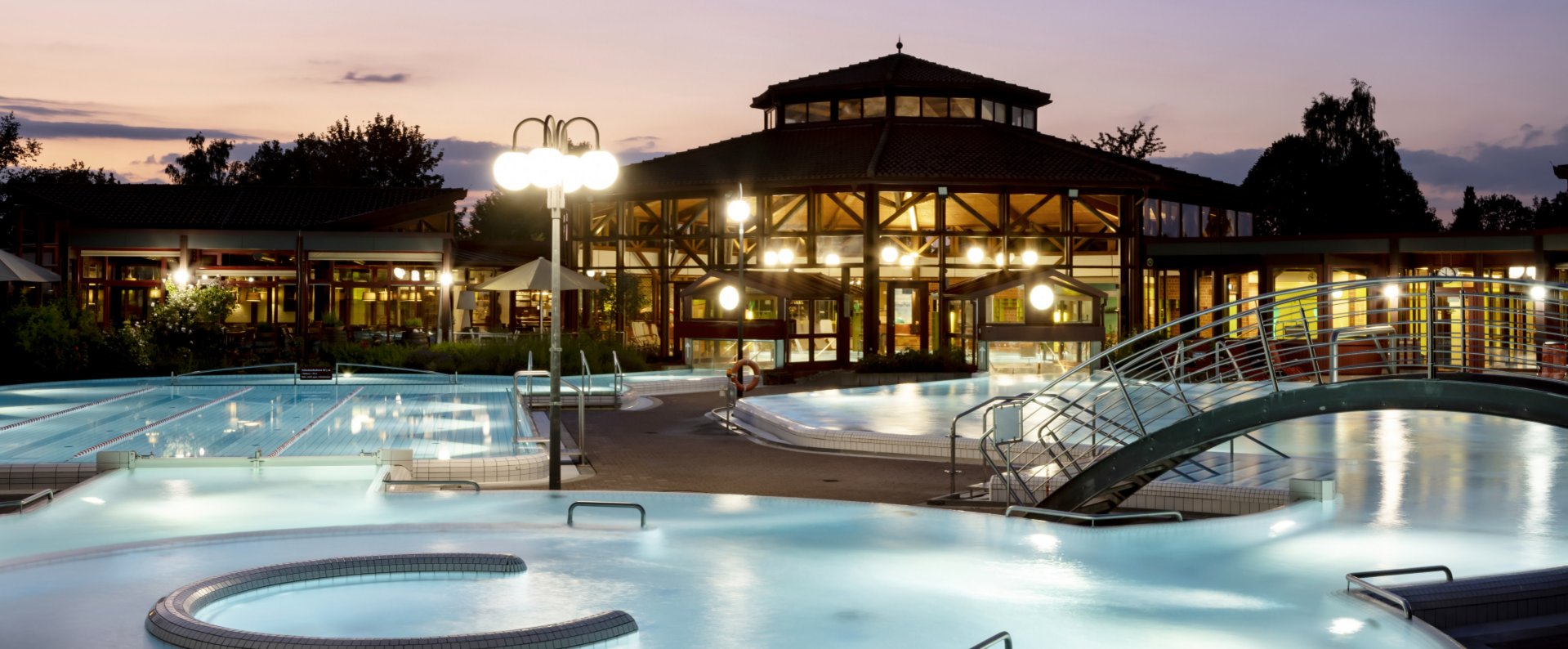 Thermalbad Sonnenhof-Therme bei Dämmerung mit beleuchteten Außenpools, einem modernen Gebäude im Hintergrund und entspannter Atmosphäre.