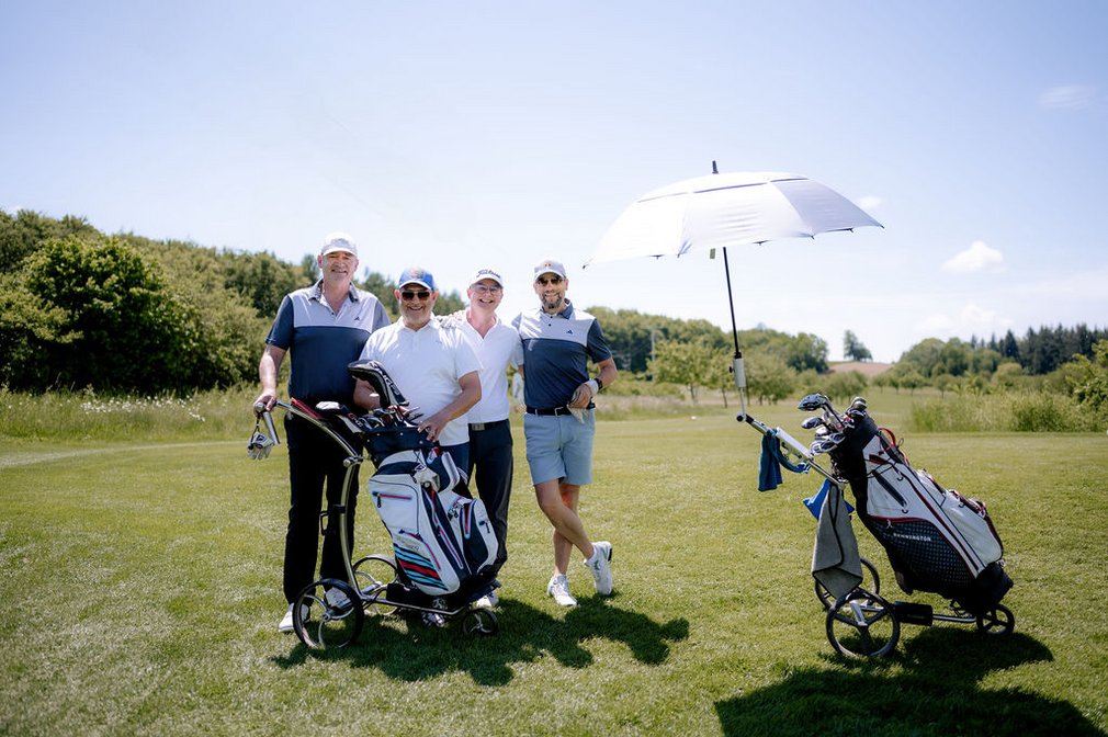 Vier Männer auf einem Golfplatz.
