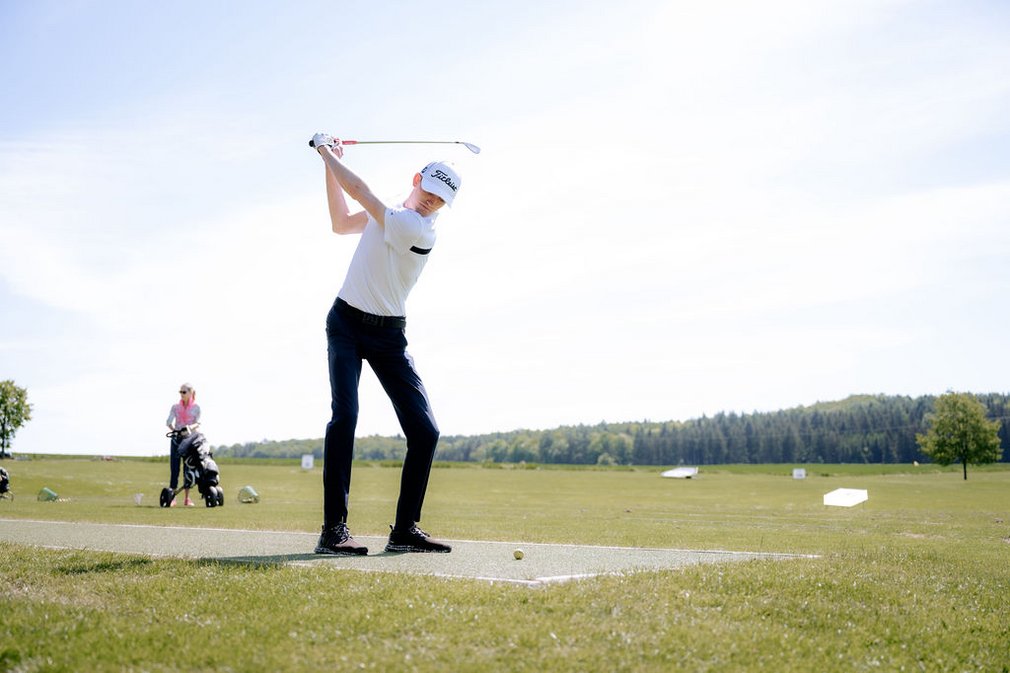 Ein Mann beim Abschlag eines Golfballs.